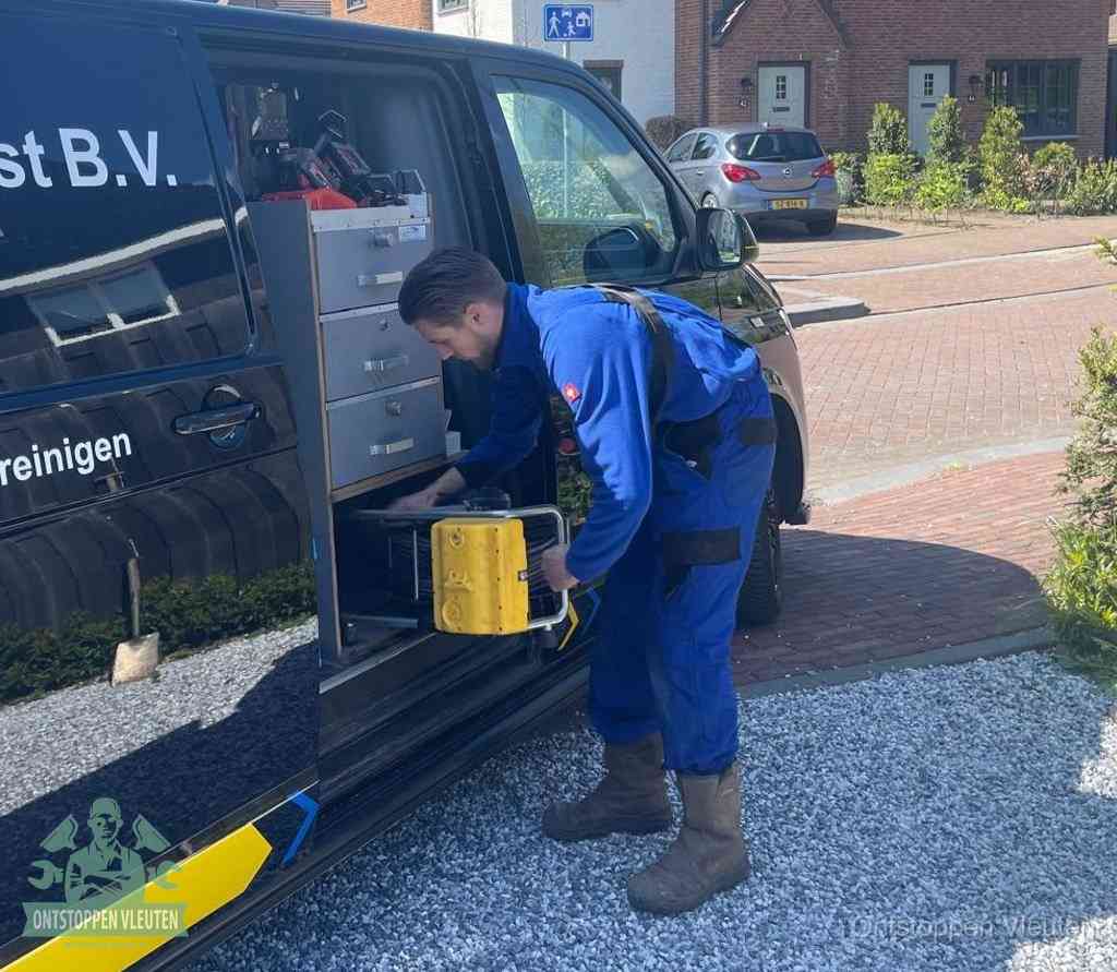 Een monteur pakt buiten op de oprit gereedschap uit de bedrijfsbus, het moment om een professional in te schakelen voor een verstopte afvoer in Vleuten