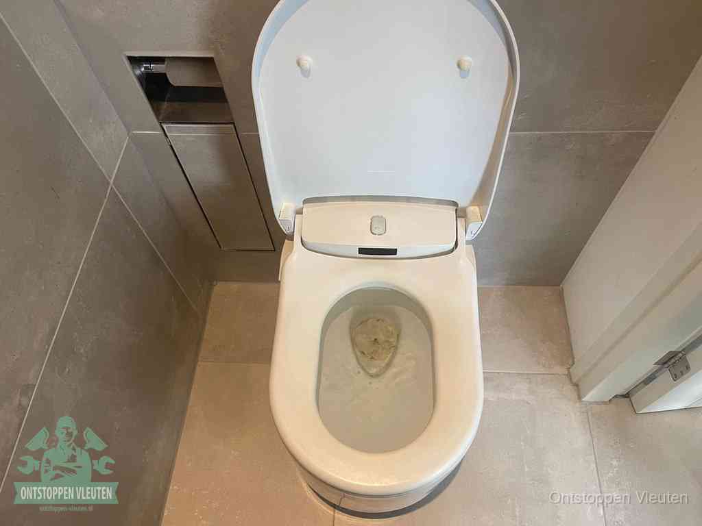 Een wit hangtoilet waarin een prop wc-papier op het water blijft drijven, een duidelijk signaal van een verstopte wc in Vleuten