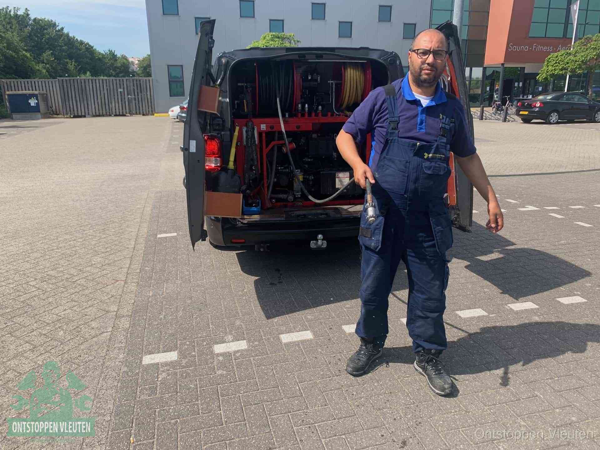 Een monteur bij zijn bestelbus met een hogedruk- en rioolreinigingsunit, klaar om de oorzaak van terugkerende wc-verstoppingen aan te pakken in Vleuten