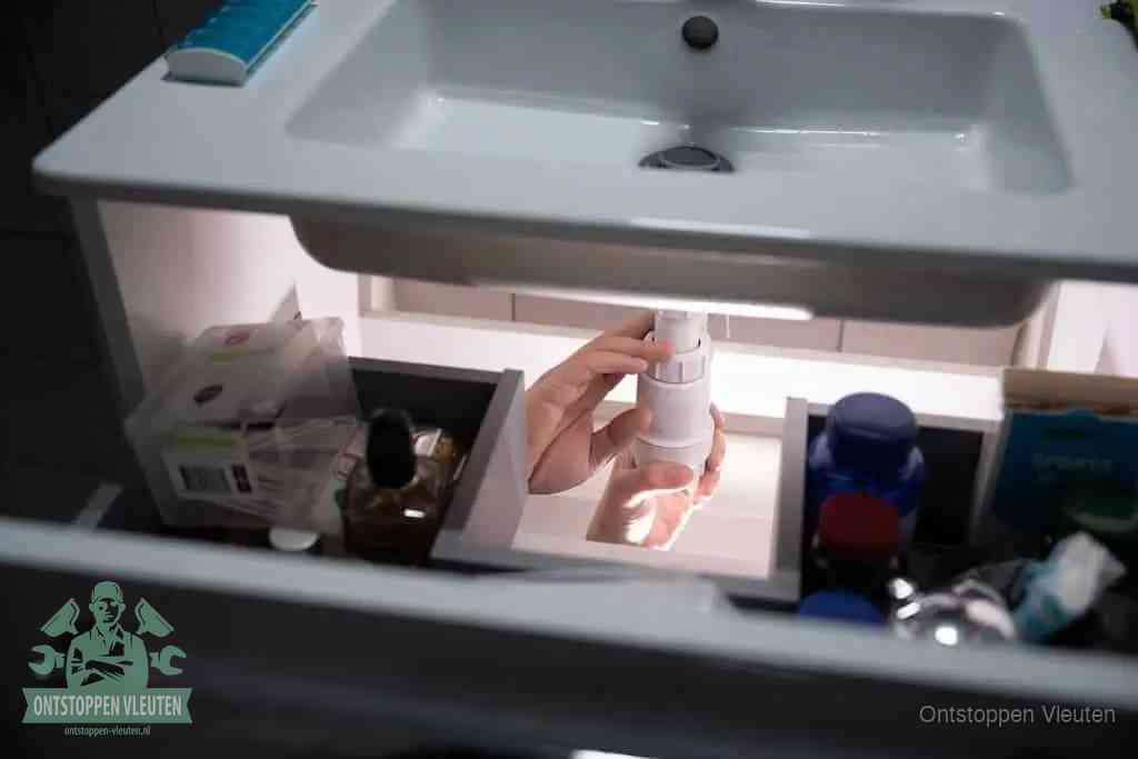 Een pompfles met zeep boven een wastafel in de toiletruimte, de warm water en afwasmiddel-methode om de wc te ontstoppen in Vleuten